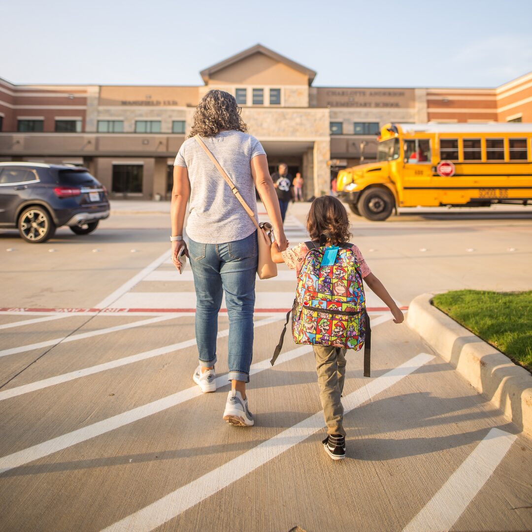 Mother walking child into school representing child custody during back to school season in San Antonio.
