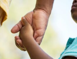 Father holding child's hand indicating successful co-parenting in summer in Texas.